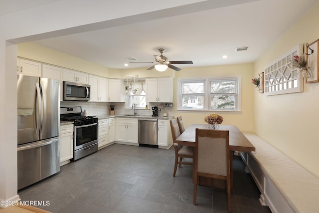 kitchen with stainless steel appliances, light countertops, visible vents, white cabinetry, and a sink