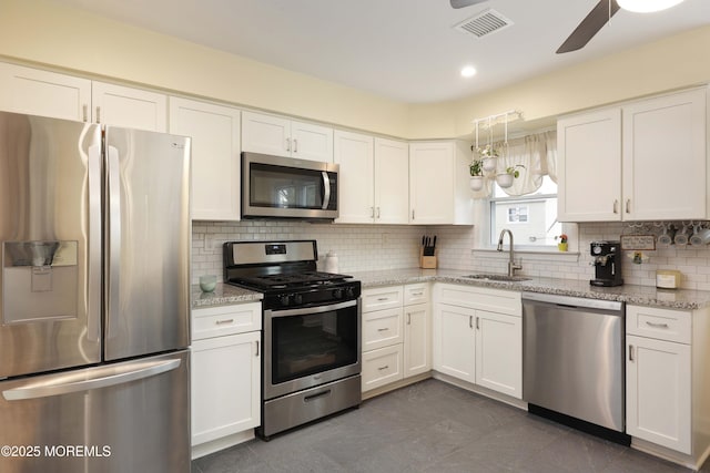 kitchen with light stone countertops, white cabinetry, appliances with stainless steel finishes, and a sink