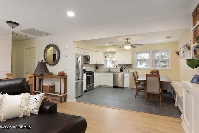 living area with recessed lighting, wood finished floors, a ceiling fan, baseboards, and visible vents