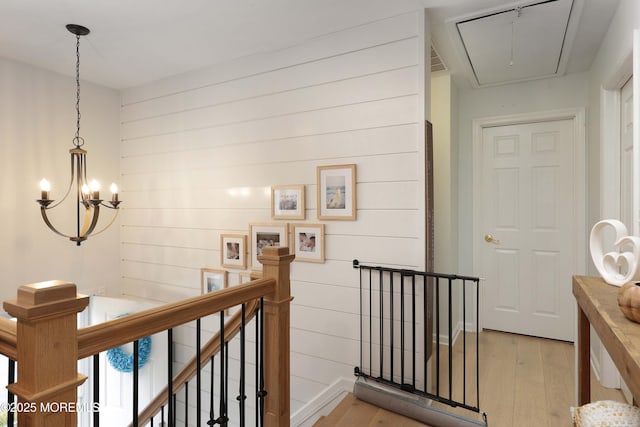 hallway featuring a notable chandelier, visible vents, light wood-style flooring, attic access, and an upstairs landing