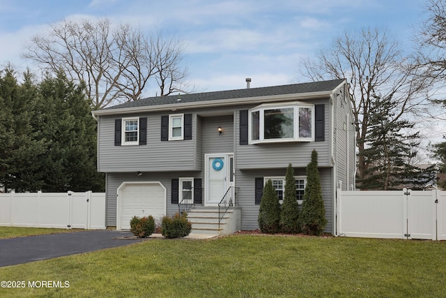 split foyer home featuring aphalt driveway, an attached garage, a gate, fence, and a front yard