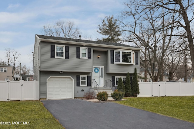 split foyer home with aphalt driveway, a gate, fence, and a front lawn