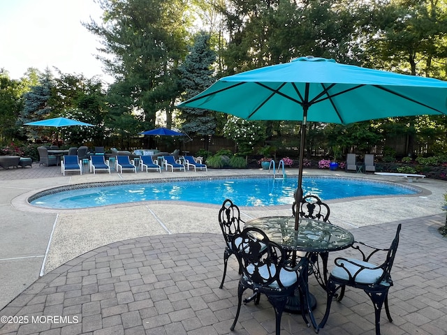 pool with a patio area and fence