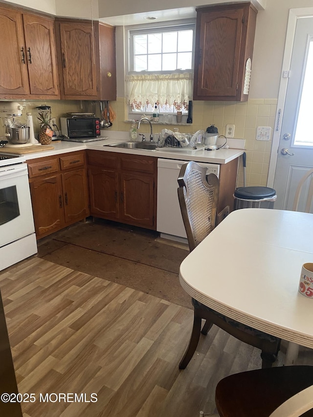 kitchen featuring white appliances, dark wood finished floors, light countertops, and a sink