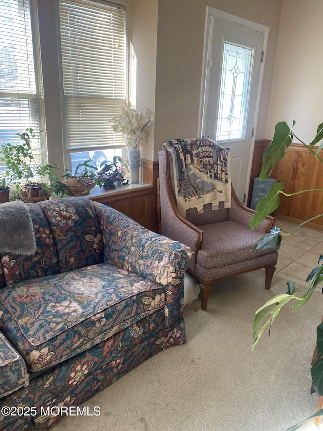 tiled living room with carpet floors, a wainscoted wall, and plenty of natural light