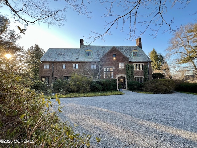 view of front facade featuring a high end roof, driveway, and a chimney