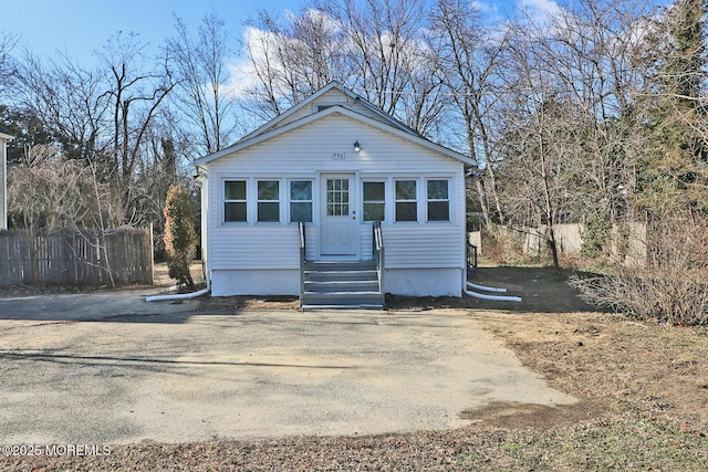 bungalow with driveway, fence, and entry steps