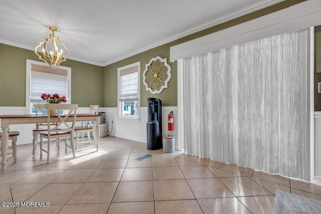 dining area featuring ornamental molding, a wainscoted wall, an inviting chandelier, and light tile patterned floors