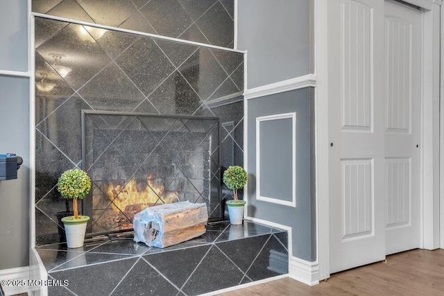 room details featuring decorative backsplash, a tiled fireplace, and wood finished floors