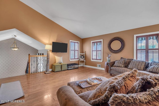 living area featuring visible vents, plenty of natural light, baseboards, and wood finished floors