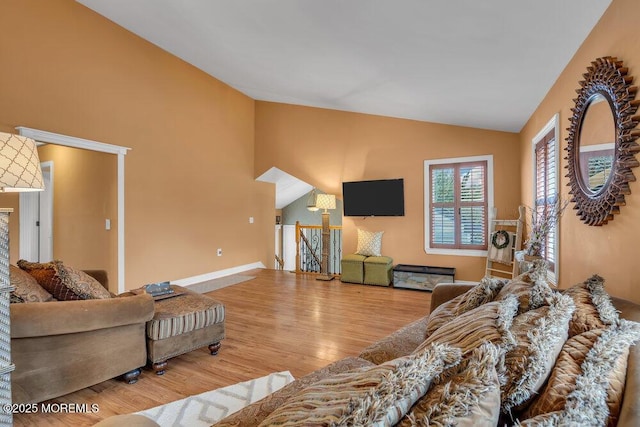 living area featuring lofted ceiling, baseboards, and wood finished floors