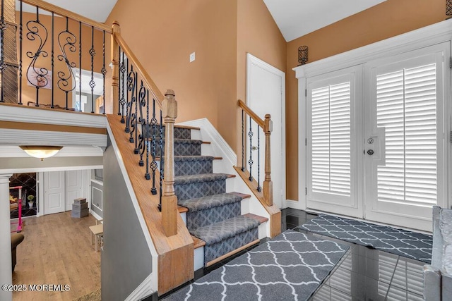 foyer entrance featuring stairs, vaulted ceiling, and wood finished floors