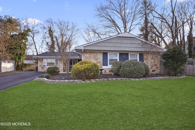 view of front facade with stone siding, fence, aphalt driveway, and a front yard