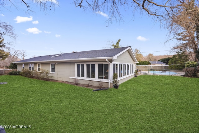 rear view of house featuring a yard, a swimming pool, fence, and a sunroom