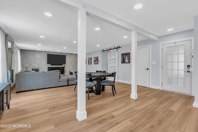 dining room featuring a barn door, recessed lighting, a fireplace, and light wood-style floors