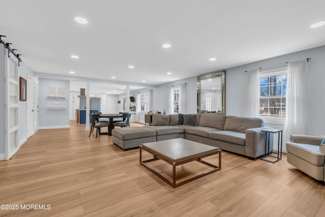 living room with light wood-style floors, recessed lighting, baseboards, and a barn door