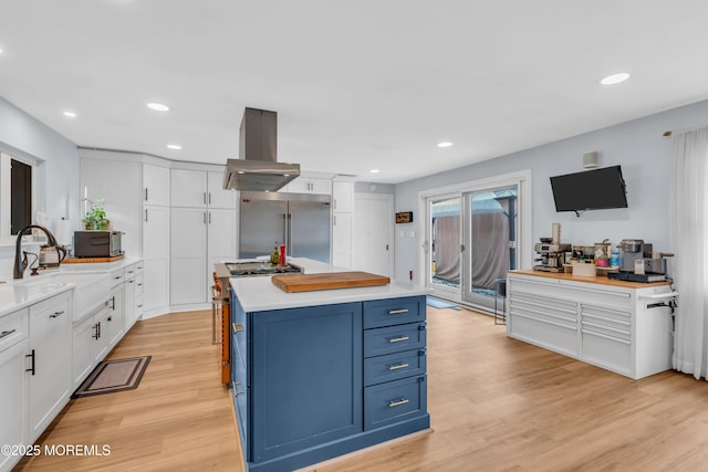 kitchen with premium appliances, a center island, light countertops, blue cabinetry, and white cabinetry