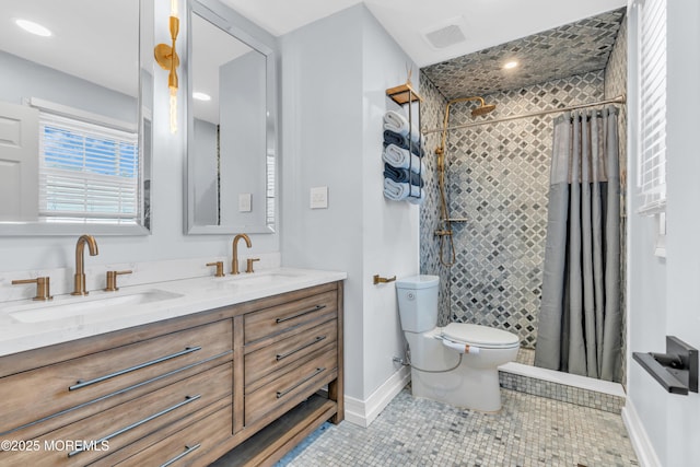 full bathroom with a tile shower, double vanity, a sink, and visible vents