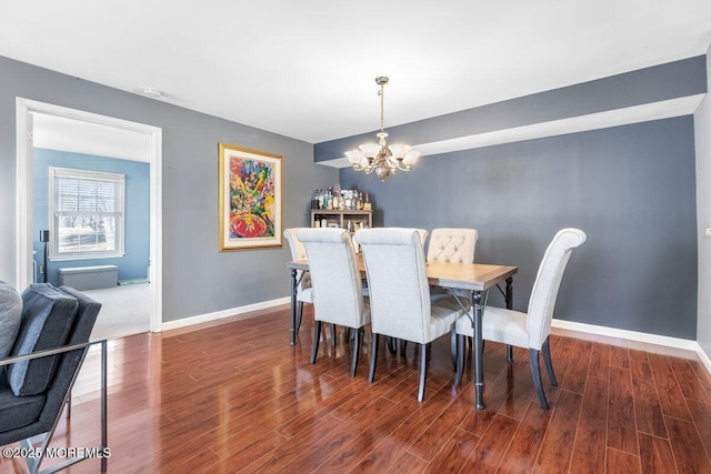 dining area featuring dark wood-style flooring, an inviting chandelier, and baseboards