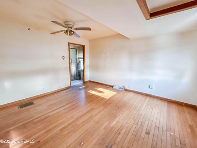 empty room with baseboards, visible vents, and light wood finished floors