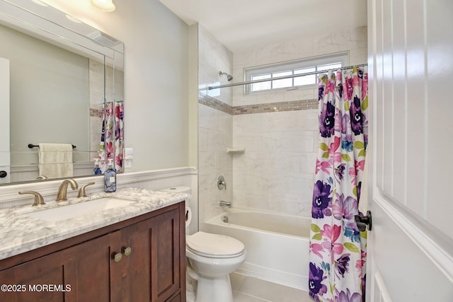 full bathroom featuring tile patterned flooring, toilet, vanity, wainscoting, and shower / bath combo