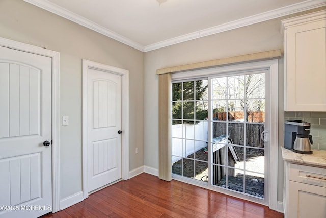 doorway with baseboards, dark wood-style flooring, and crown molding