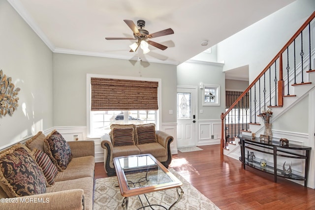 living room with crown molding, stairs, wood finished floors, and wainscoting