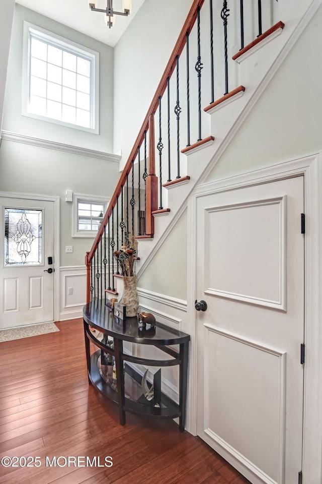 foyer featuring dark wood-style floors, wainscoting, plenty of natural light, and stairs