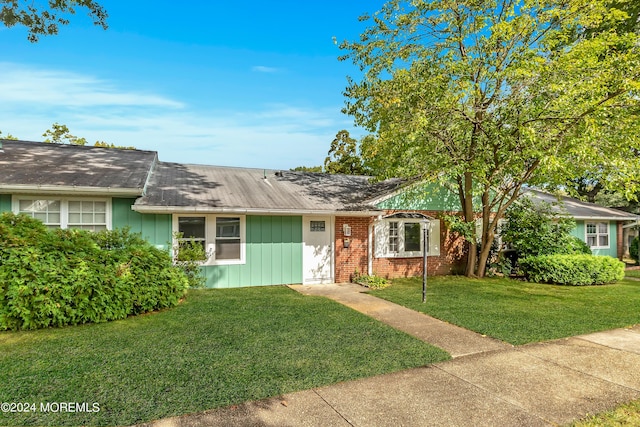 single story home featuring a front lawn, board and batten siding, and brick siding