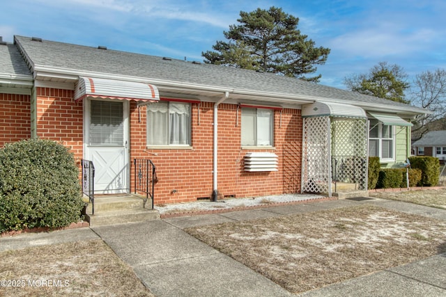 bungalow-style house with crawl space, brick siding, and roof with shingles