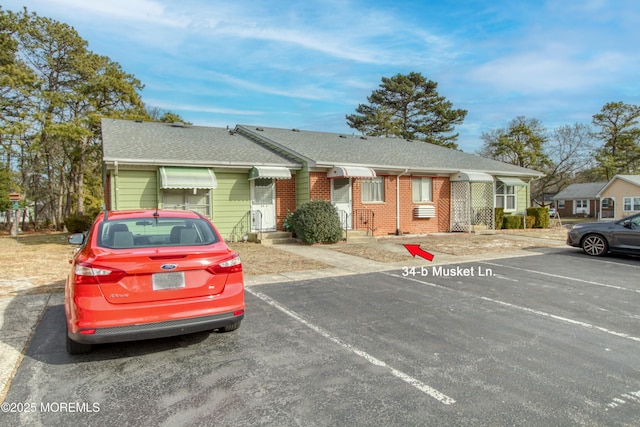 single story home with uncovered parking, brick siding, and a shingled roof