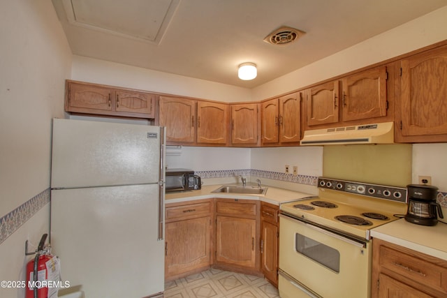 kitchen featuring white appliances, under cabinet range hood, light countertops, and a sink