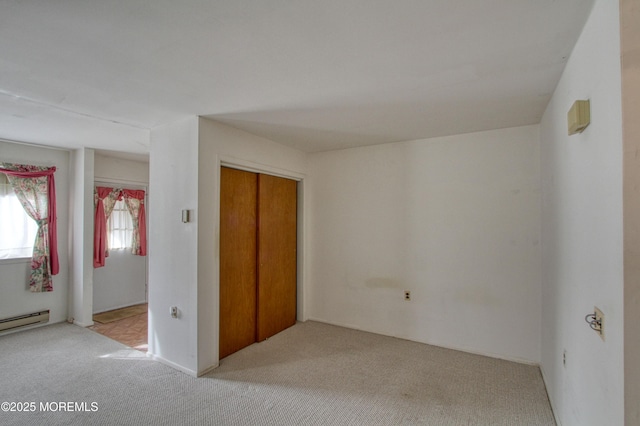 unfurnished bedroom with a baseboard radiator and light colored carpet