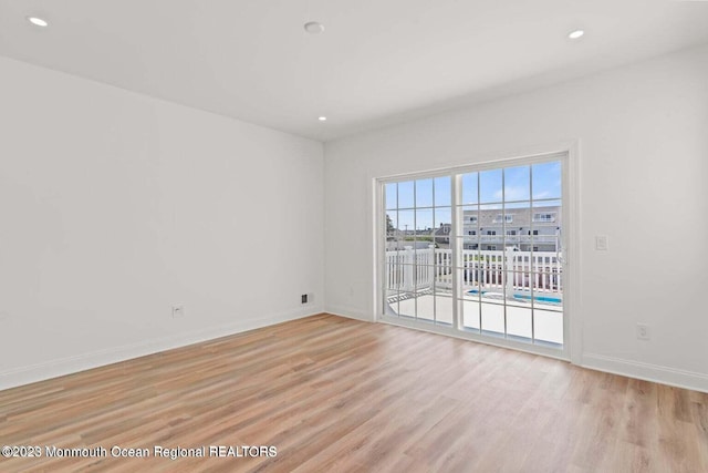 spare room with light wood finished floors, recessed lighting, and baseboards