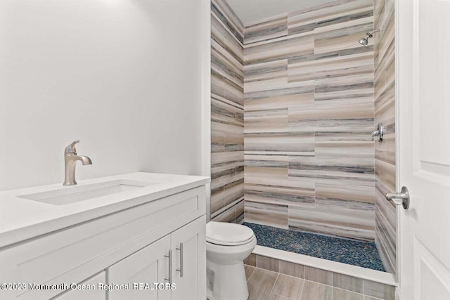 bathroom featuring toilet, a shower stall, and vanity