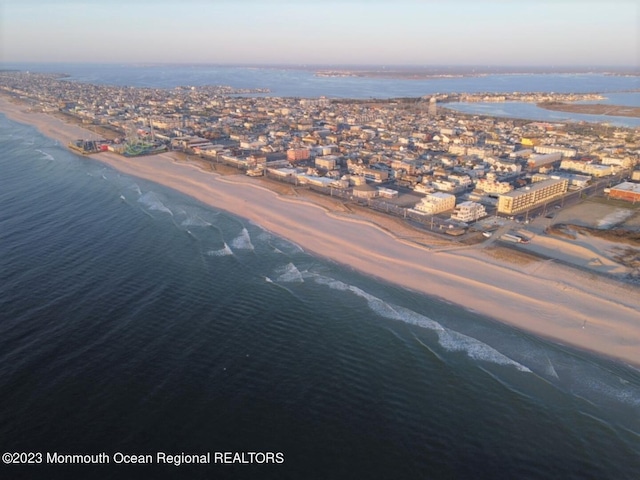 aerial view at dusk with a beach view and a water view