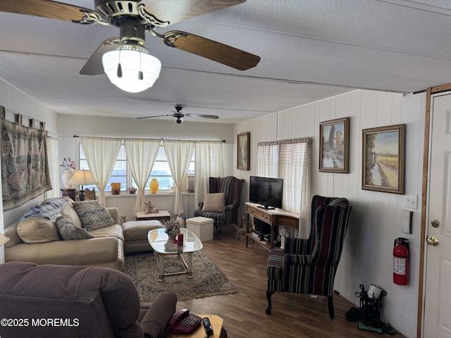 living area with ceiling fan, a textured ceiling, and wood finished floors