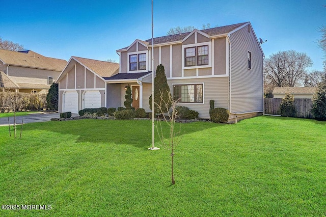 tudor-style house featuring a garage, driveway, a front lawn, and fence