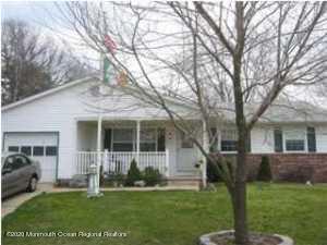 view of front of house with an attached garage, covered porch, and a front lawn