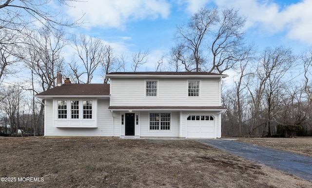 view of front of property with aphalt driveway, a porch, a chimney, and a garage