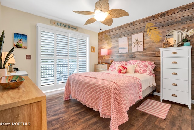 bedroom with dark wood-type flooring, wooden walls, and a ceiling fan