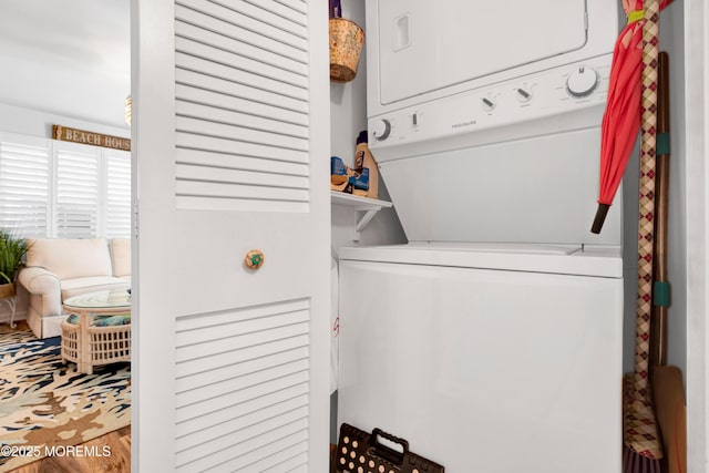 laundry area with wood finished floors, stacked washer and clothes dryer, and laundry area