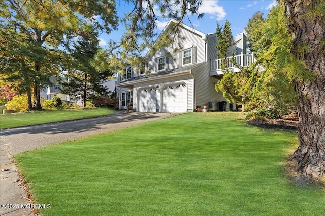 traditional-style house featuring a garage, driveway, a balcony, and a front lawn