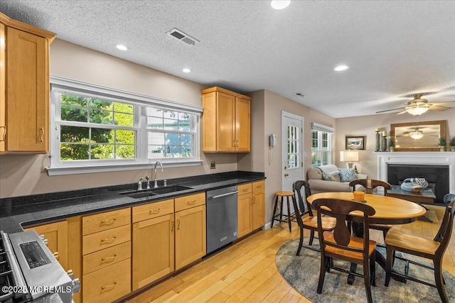 kitchen with dark countertops, stainless steel appliances, a sink, and open floor plan