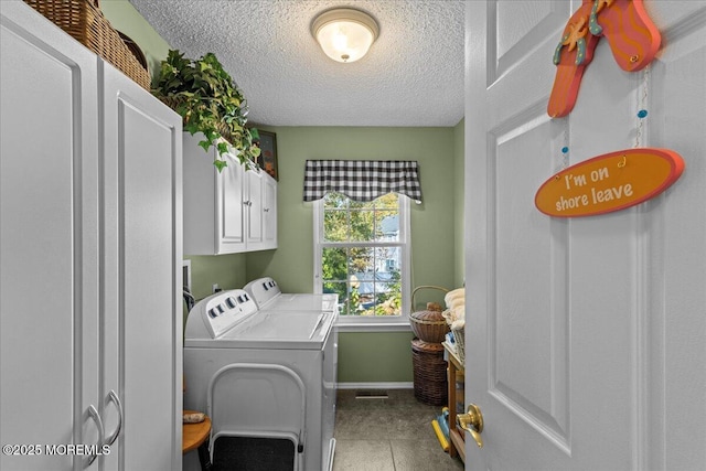 laundry room with a textured ceiling, tile patterned flooring, baseboards, washer and dryer, and cabinet space