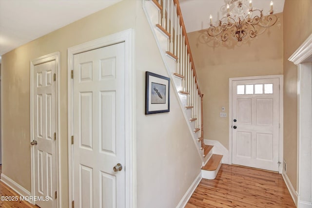 foyer entrance with a chandelier, light wood-style flooring, baseboards, and stairs