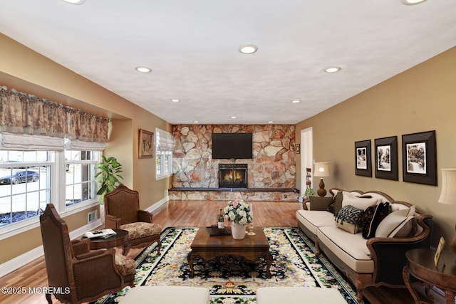 living room featuring light wood-style floors, a fireplace, baseboards, and recessed lighting