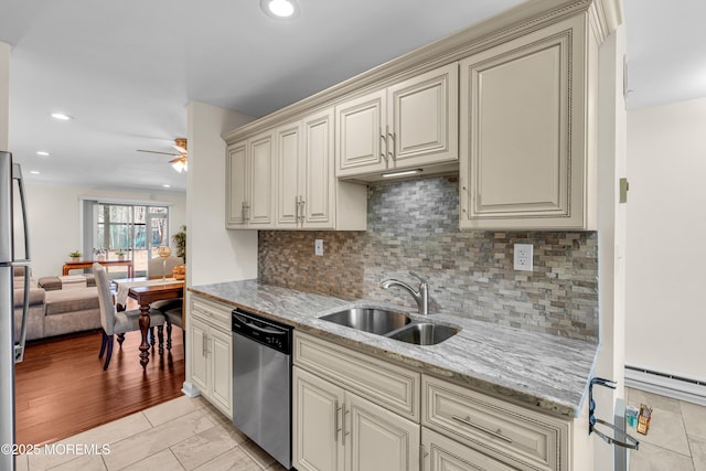 kitchen featuring cream cabinetry, a baseboard heating unit, a sink, light stone countertops, and dishwasher