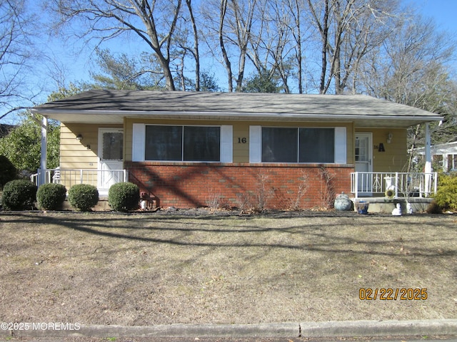 view of front facade featuring a porch, brick siding, and a front lawn