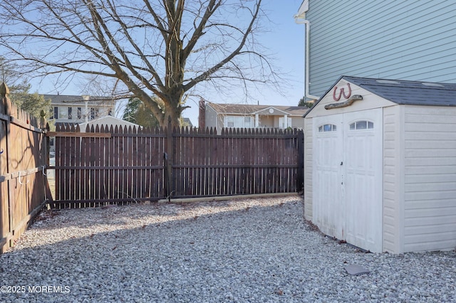 view of yard with a storage shed, a fenced backyard, and an outbuilding